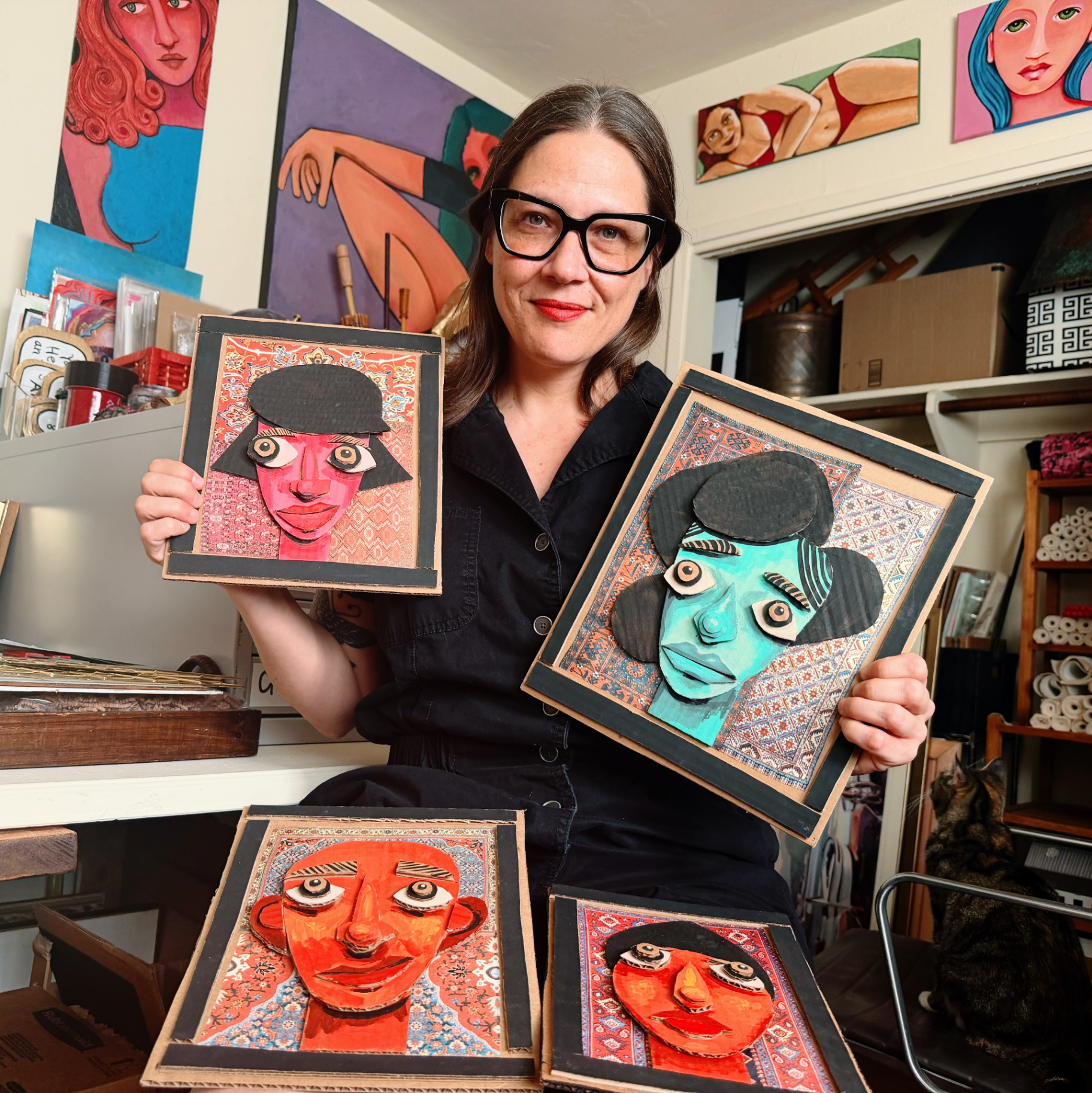 Aurora Lucia-Levey in her studio holding cardboard face artworks