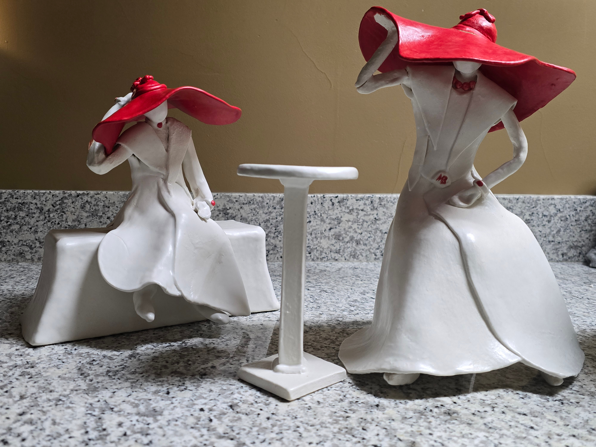 Two porcelain figures in red wide-brim hats