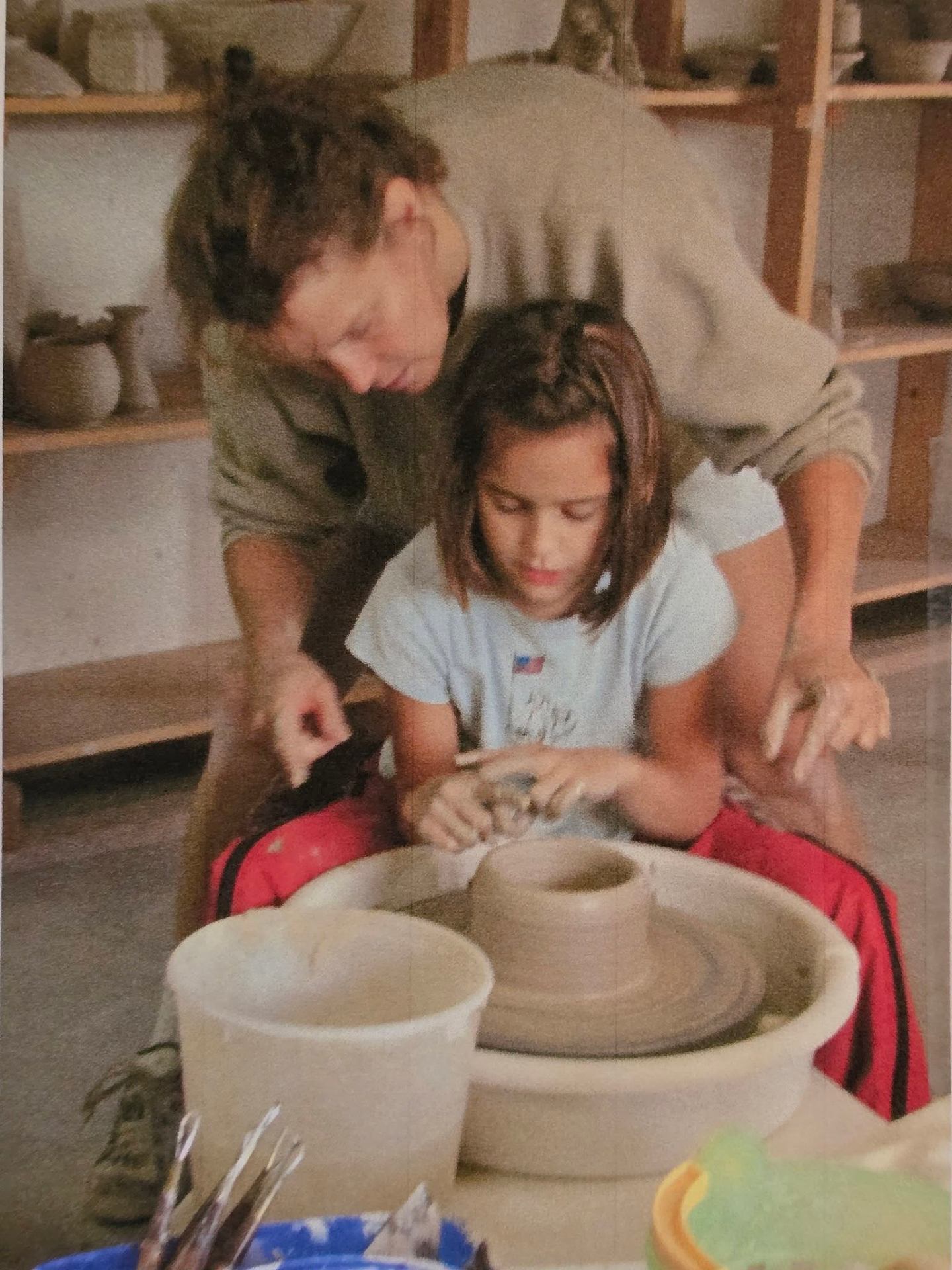 Morgan Britt guiding a young student at the pottery wheel in the White Rabbit studio